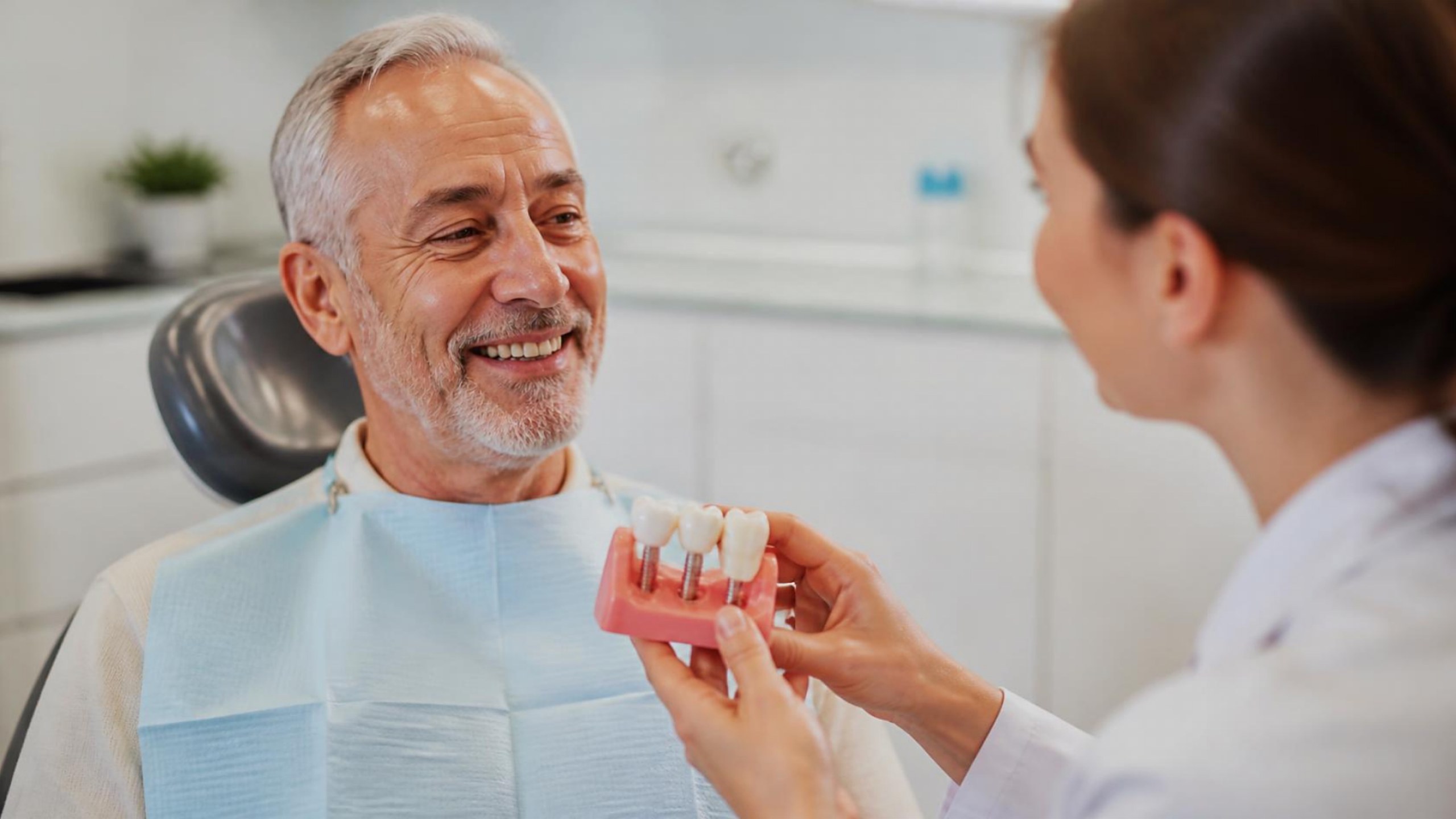 Paciente sénior sorridente em consulta de implantes dentários
